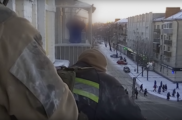 Kapkanov, in blue with his hands over his head, standing on his 4th-floor balcony. Image: npu.gov.ua