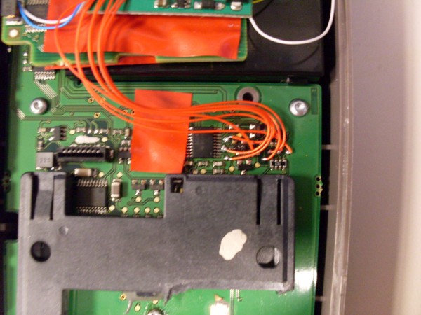 A close-up showing the orange wires from the skimmer soldered to the PIN pad.